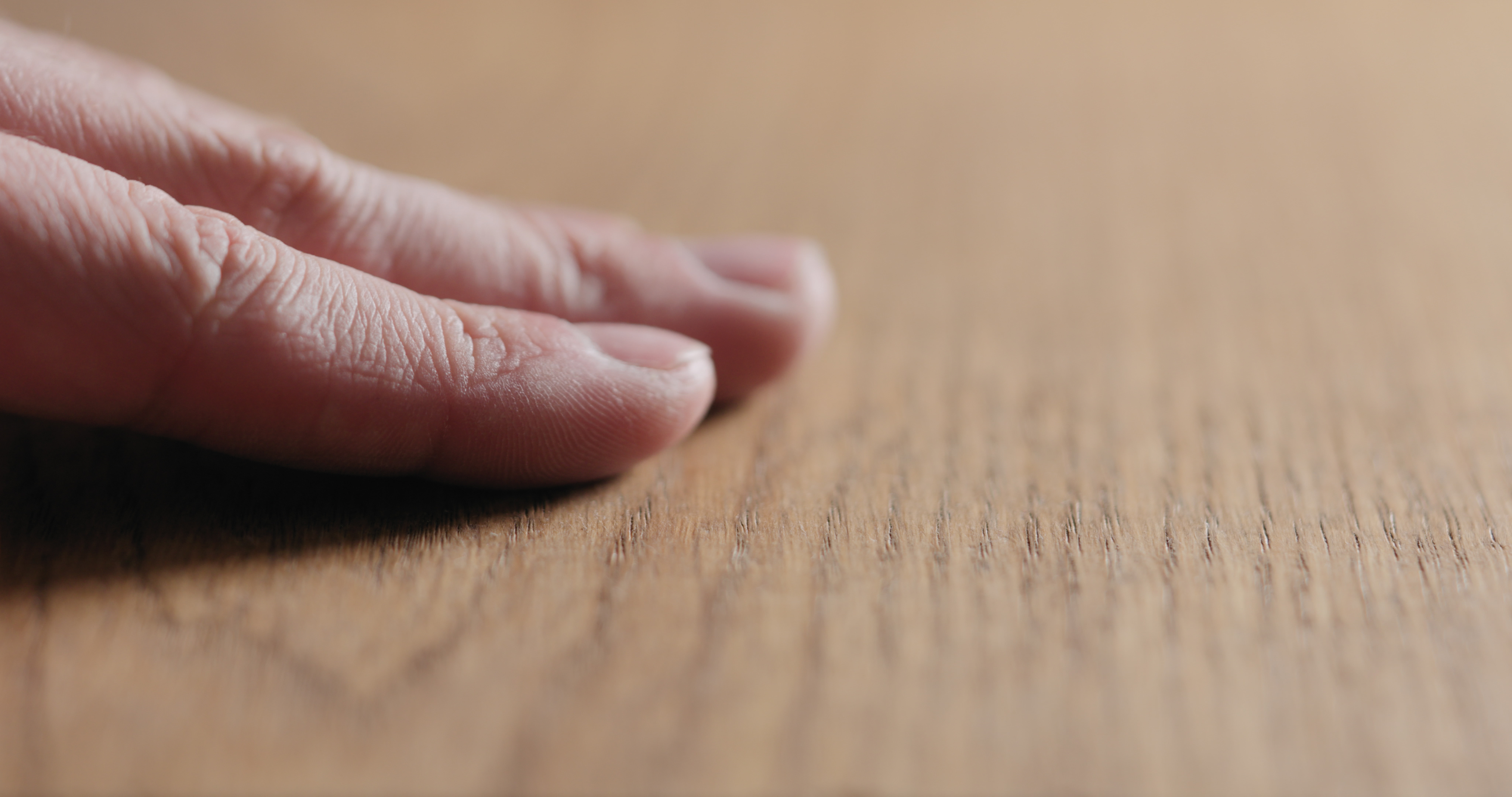 Man's hand touching wood. How do you get scratches out of hardwood floor
